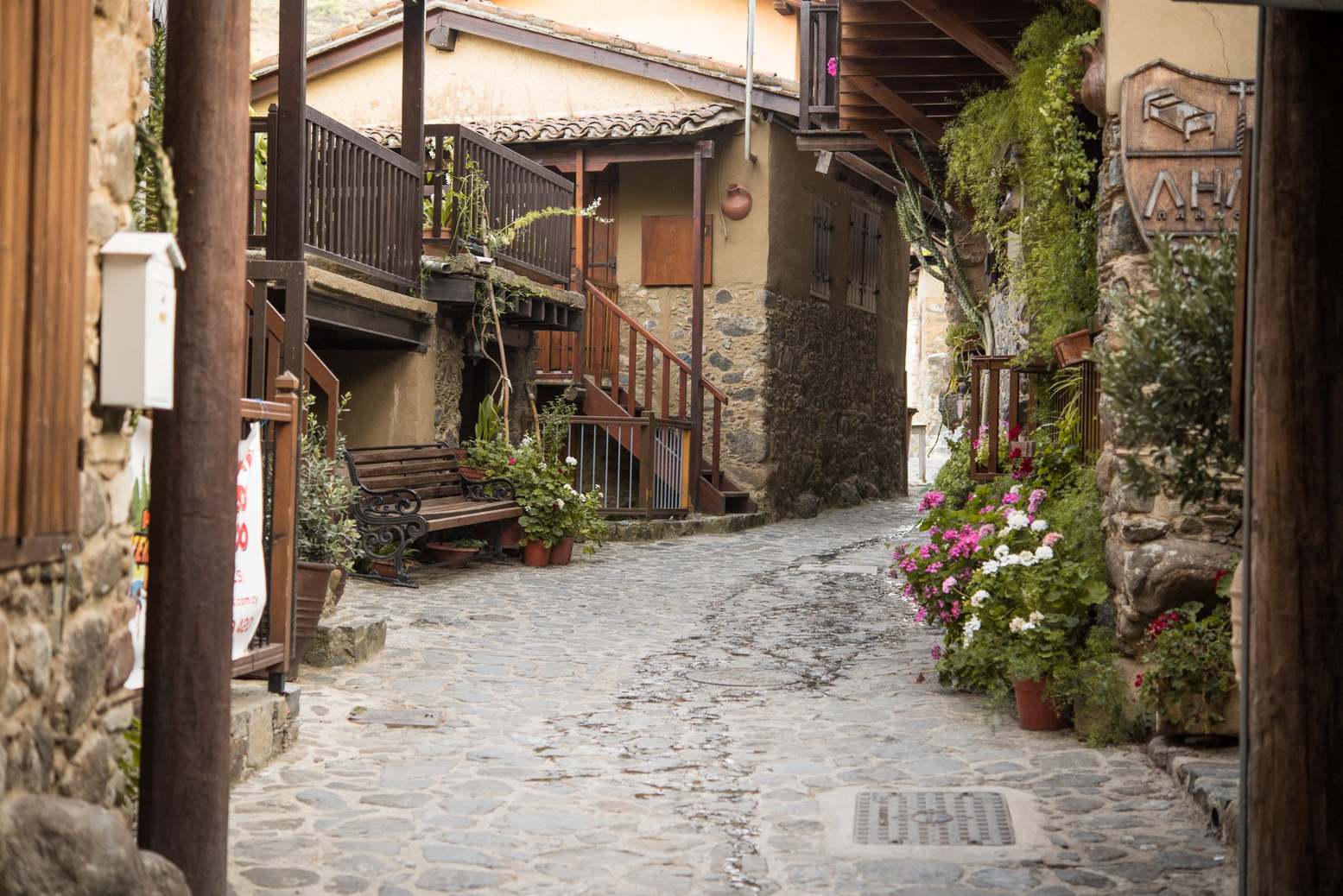 Cobblestone alley with flowers and a wooden bench in Kakopetria, Cyprus