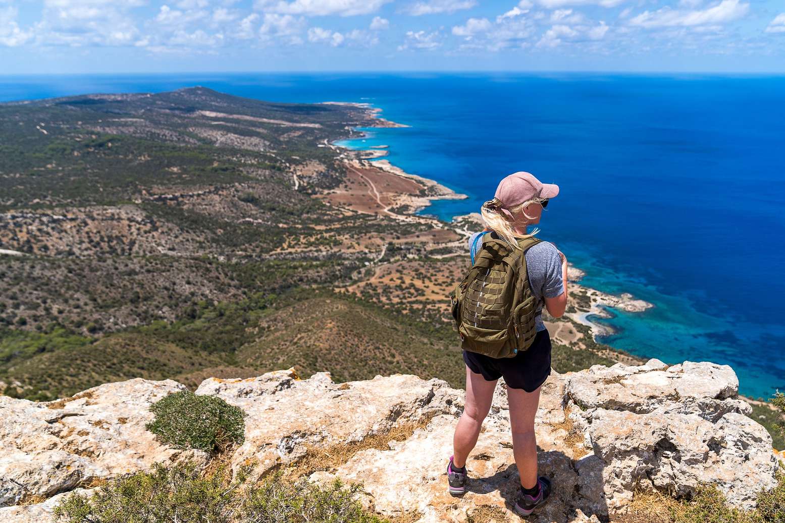 Hiker looking out from a rocky clifftop above the sea
