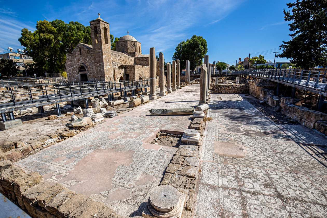 Ancient ruins and mosaic floor beside a stone church in Paphos